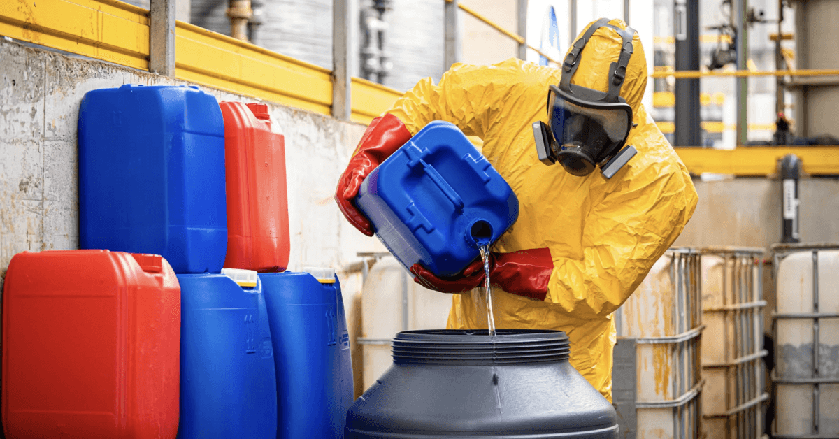 Chemical worker or technologist in yellow protection suit and gas mask making sulfuric acid for industry