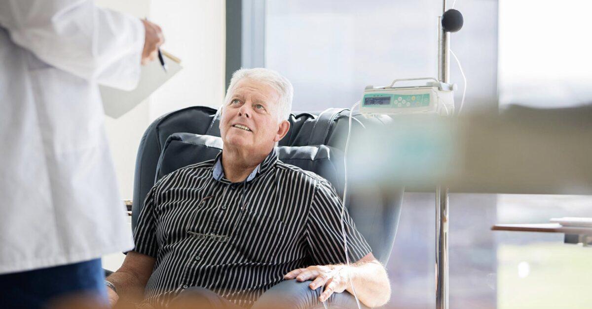 Doctor talking to patient receiving medical treatment in hospital ward stock photo