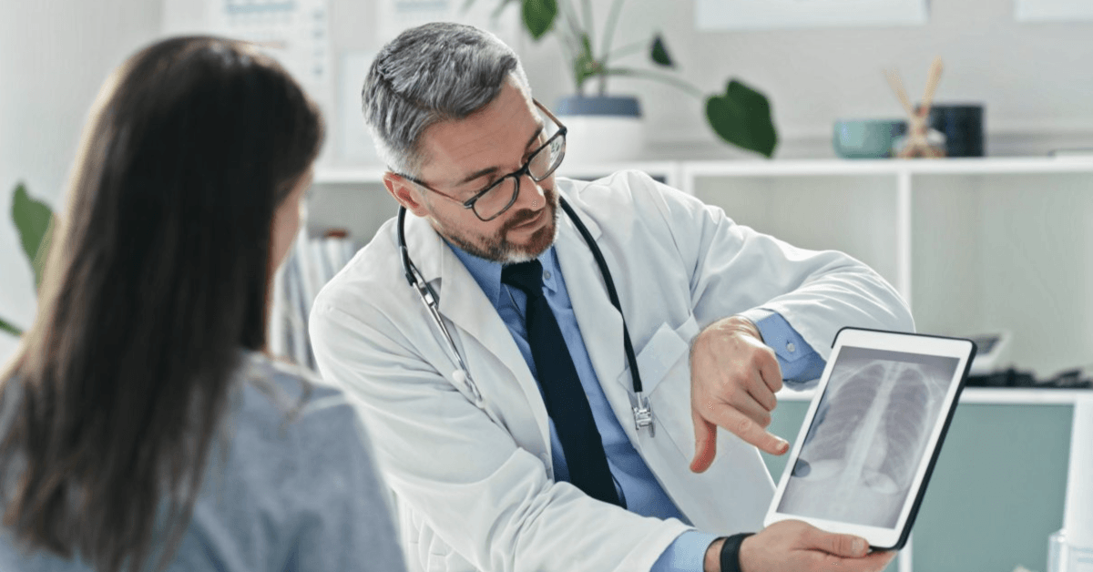 Shot of a mature doctor sitting with his patient and showing her x-rays on a digital tablet