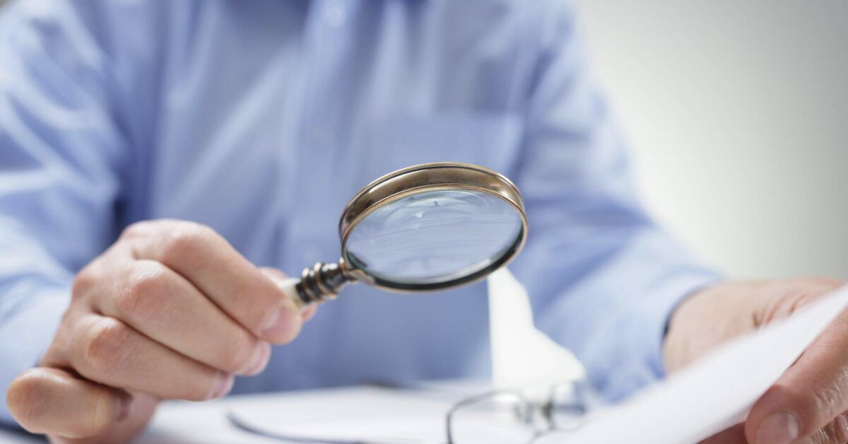 Businessman with magnifying glass reading documents