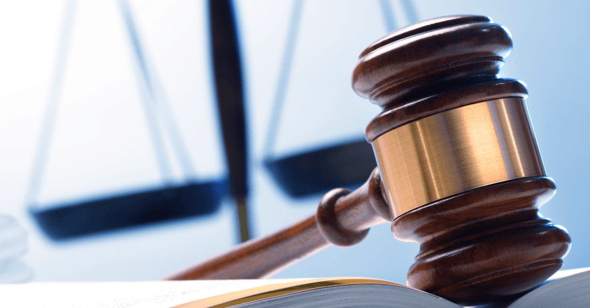 Judge’s gavel resting on a book with scales of justice in the background.